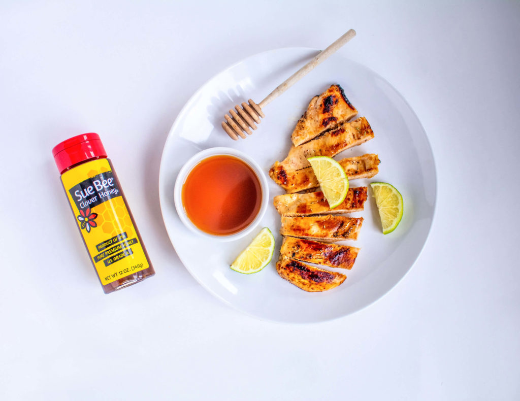 Photo of a bottle of Sue Bee® honey and a plate of chicken. 