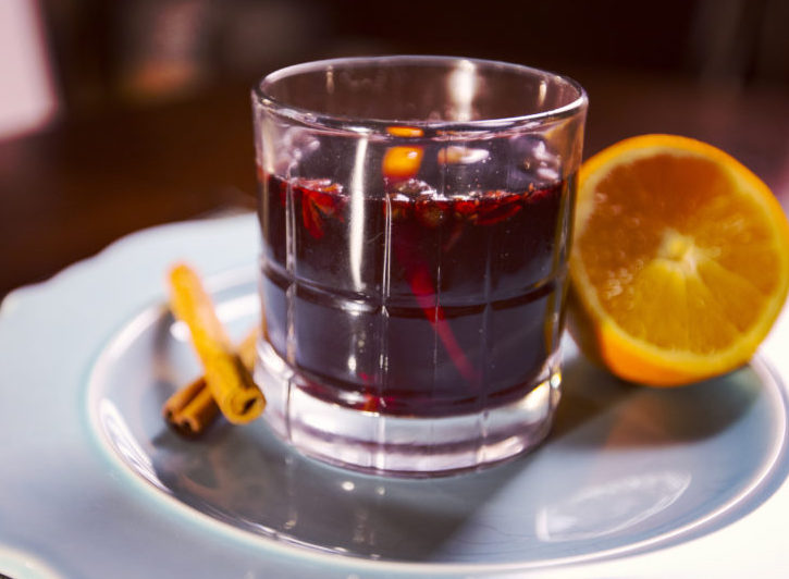 Photo of mulled wine in a glass with orange garnish.